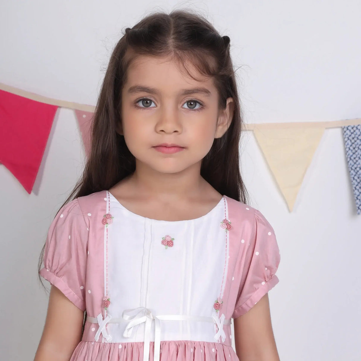 "Close-up of a girl dressed in a pink embroidered cotton dot printed dress."