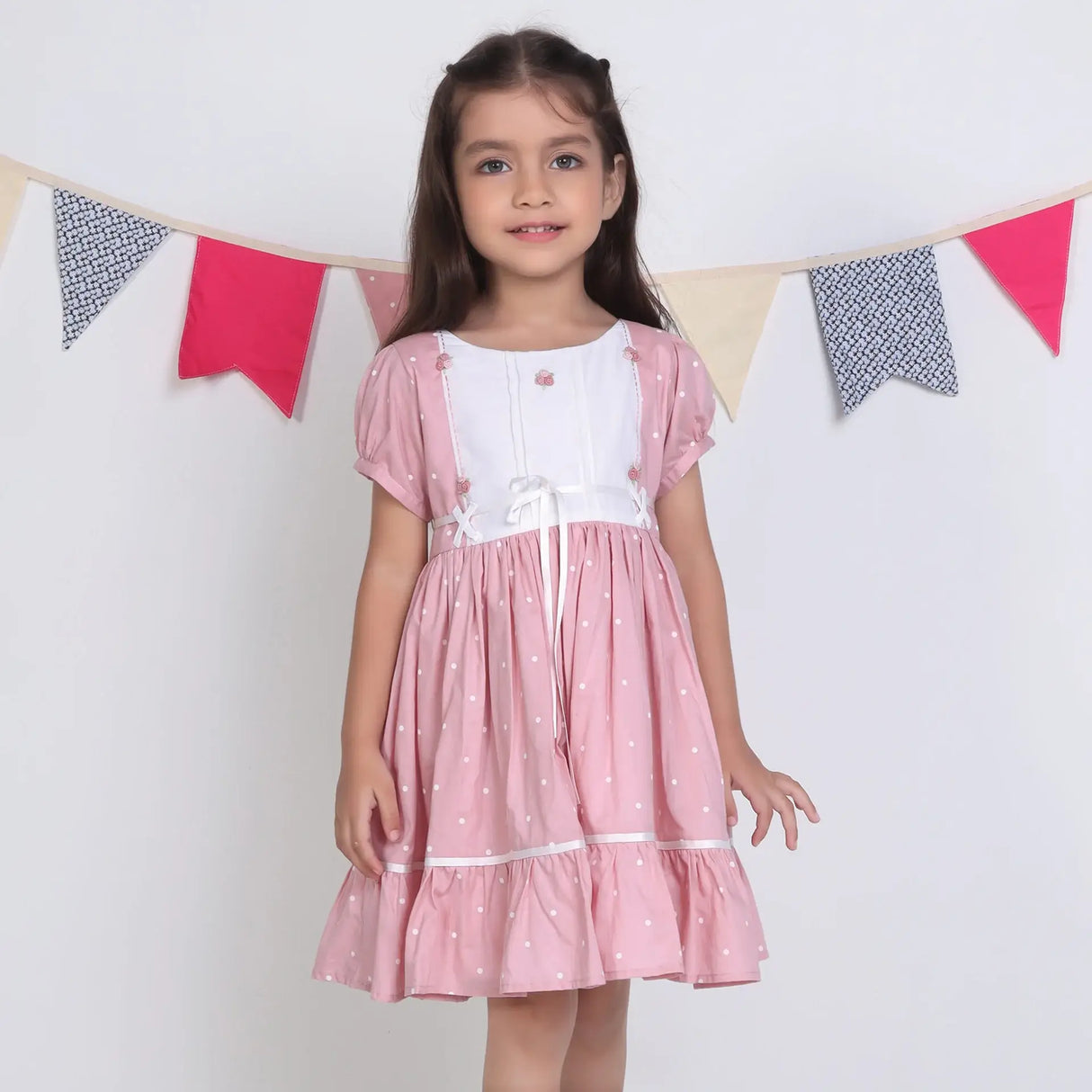 "A girl dressed in a pink embroidered cotton dot printed dress."