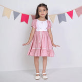 "A little girl posing in a pink embroidered cotton dot printed dress."