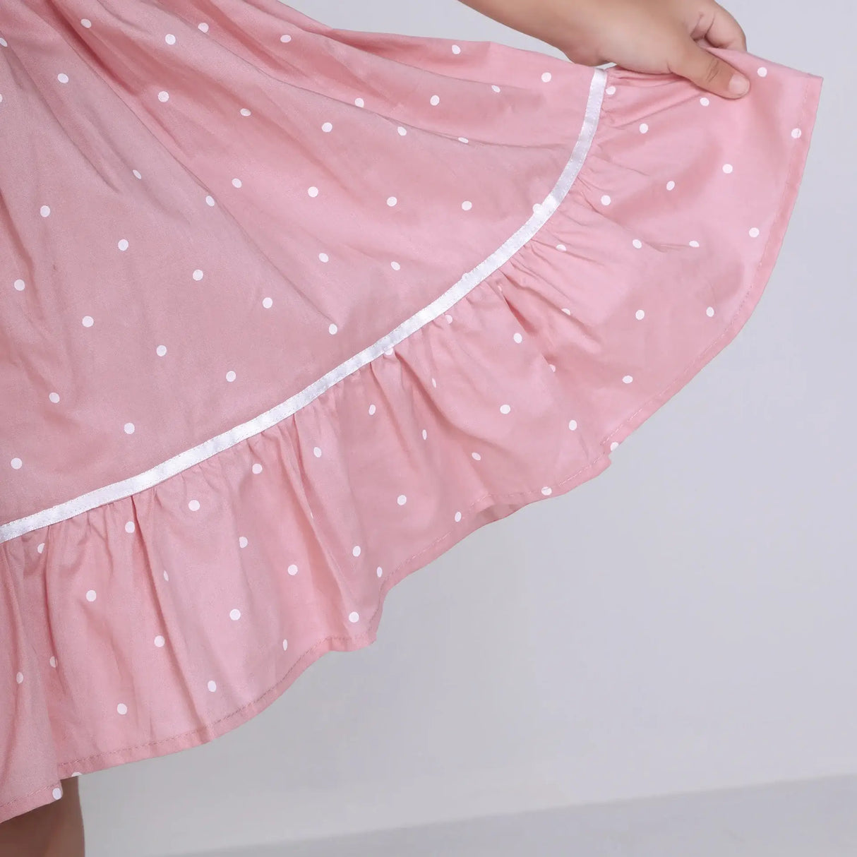 "Close-up of the skirt of a pink embroidered cotton dot printed dress."