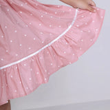 "Close-up of the skirt of a pink embroidered cotton dot printed dress."