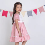 "Side pose of a girl dressed in a pink embroidered cotton dot printed dress."