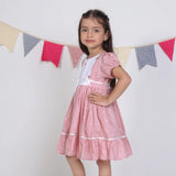 "Side pose of a girl dressed in a pink embroidered cotton dot printed dress."
