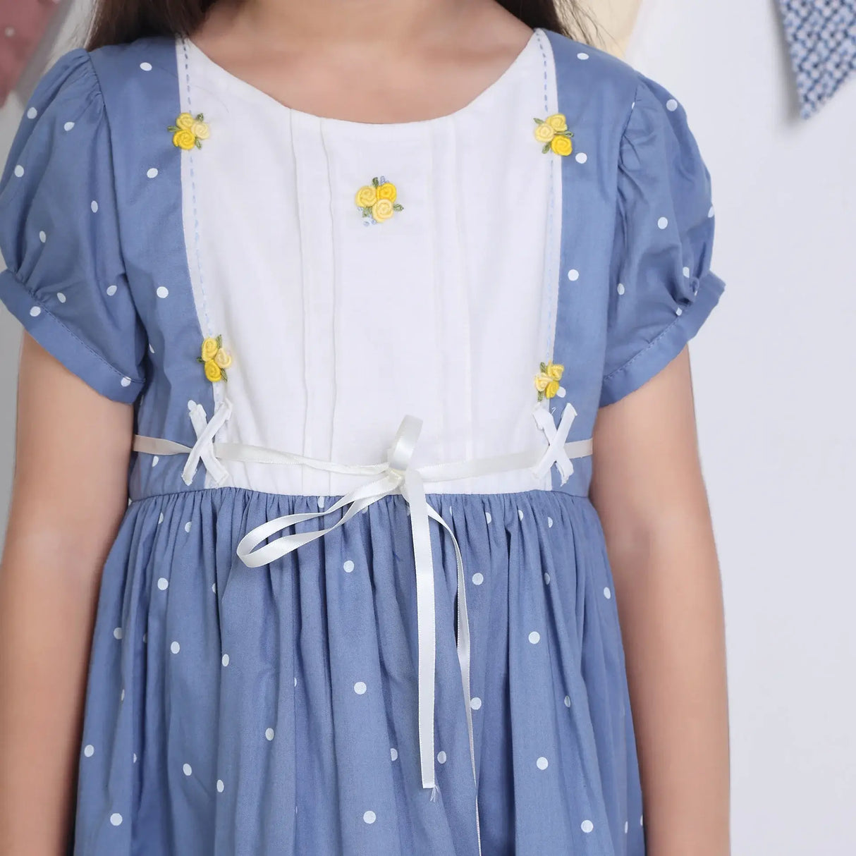 "Close-up of a girl dressed in a blue embroidered cotton dot printed dress."