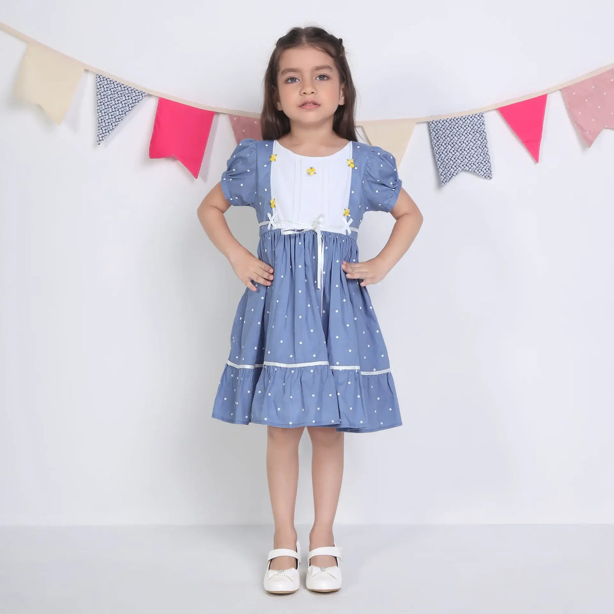 "A girl dressed in a blue embroidered cotton dot printed dress."