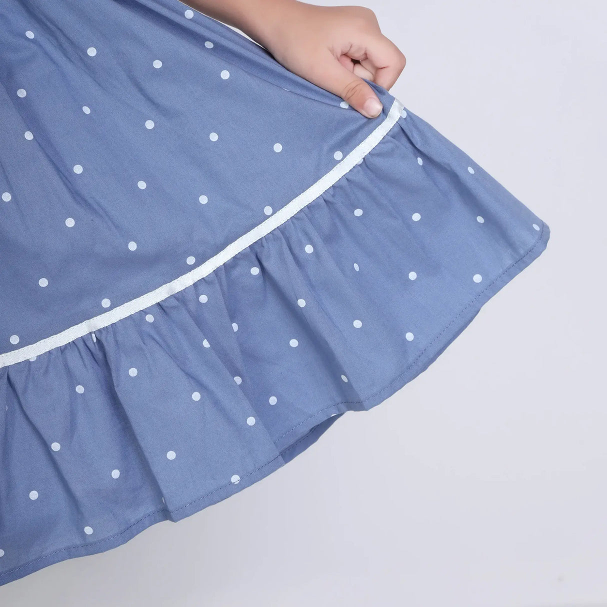 "Close-up of the skirt of a blue embroidered cotton dot printed dress."