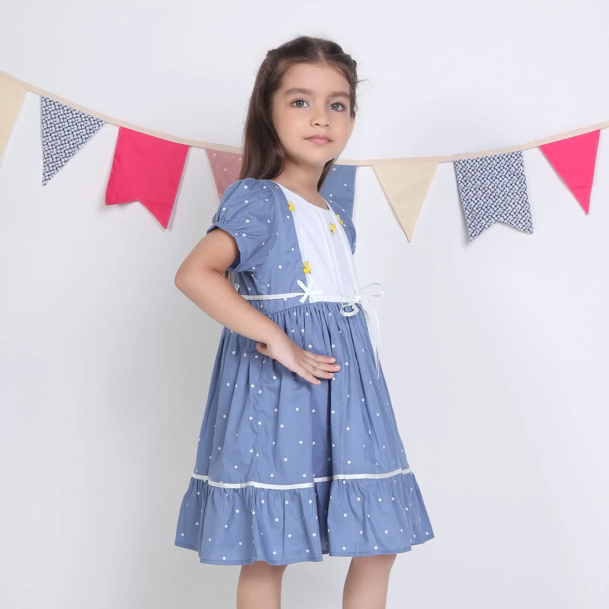 "Side pose of a girl dressed in a blue embroidered cotton dot printed dress."