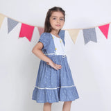 "Side pose of a girl dressed in a blue embroidered cotton dot printed dress."