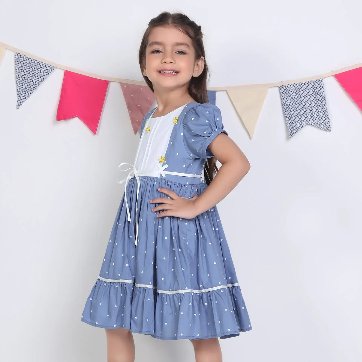 "Side pose of a girl dressed in a blue embroidered cotton dot printed dress."