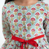 Close-up of a girl dressed in a blue and red printed long sleeves cotton dress with contrast trims.