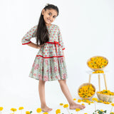 Side view of a girl dressed in a blue and red printed long sleeves cotton dress with contrast trims.