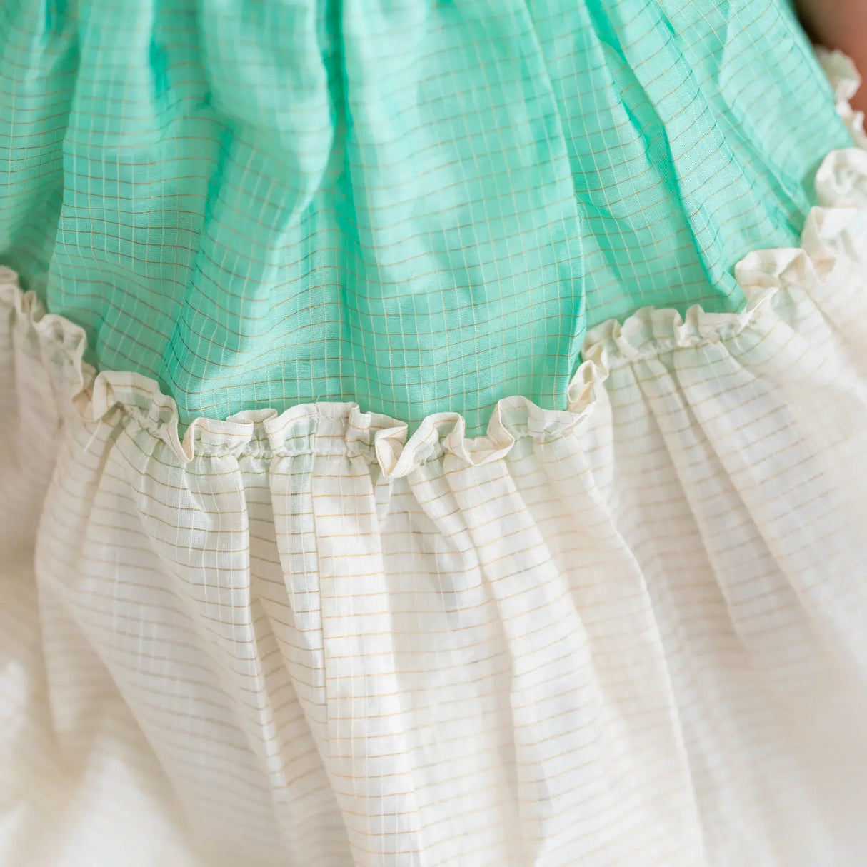"Close-up of the ruffles on the green zari checked cotton silk half sleeves dress."