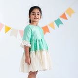 "Side view of a girl in a green zari checked cotton silk half sleeves dress."