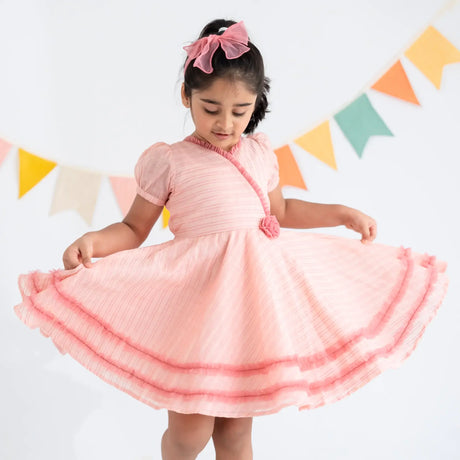 "A little girl twirling in a pink crossover chanderi puffed sleeves dress."