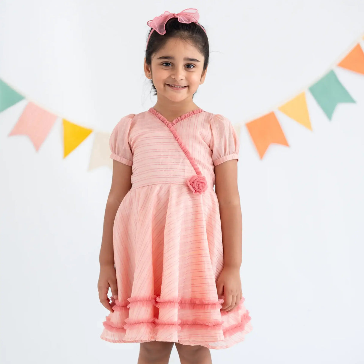 "A girl dressed in a pink crossover chanderi puffed sleeves dress."