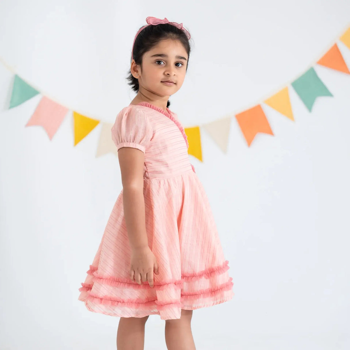 "Side view of a girl in a pink crossover chanderi puffed sleeves dress."
