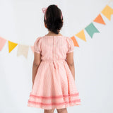 "Back view of a girl in a pink crossover chanderi puffed sleeves dress."