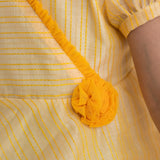 "Close-up of the crossover neckline and tulle rose on the yellow crossover chanderi puffed sleeves dress."