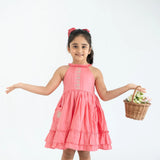 "A little girl posing in a coral embroidered cotton satin sleeveless dress with pockets."