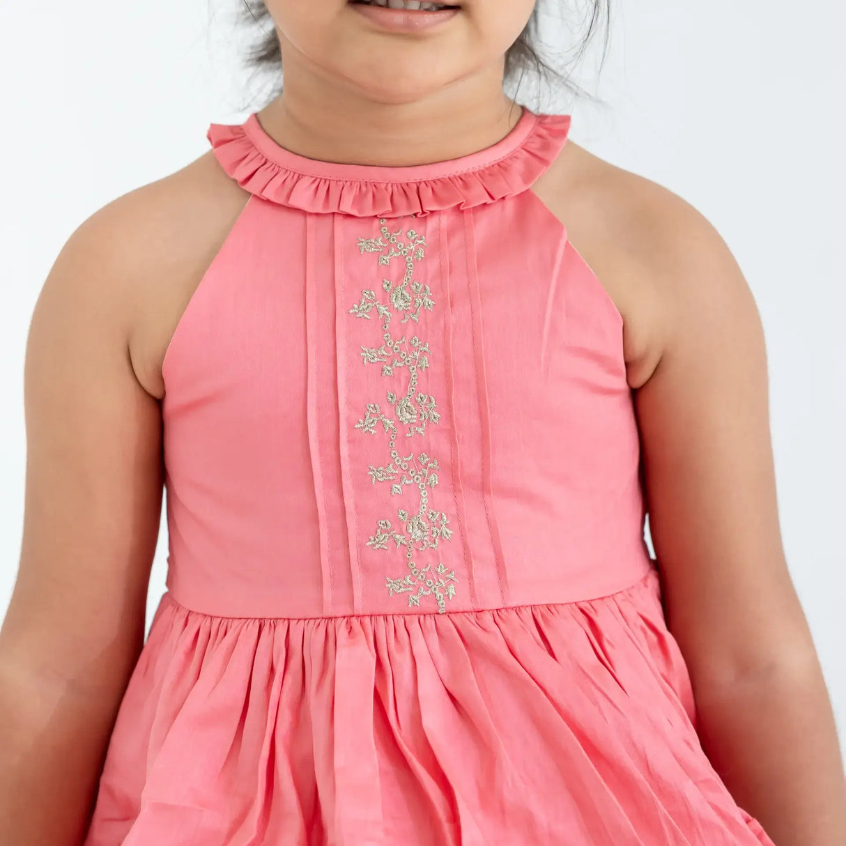 "Close-up of a girl dressed in a coral embroidered cotton satin sleeveless dress."