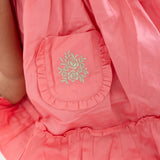 "Close-up of the pocket details in a coral embroidered cotton satin dress."