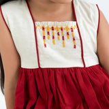 Close-up of the hand embroidery on a red sleeveless cotton dress.