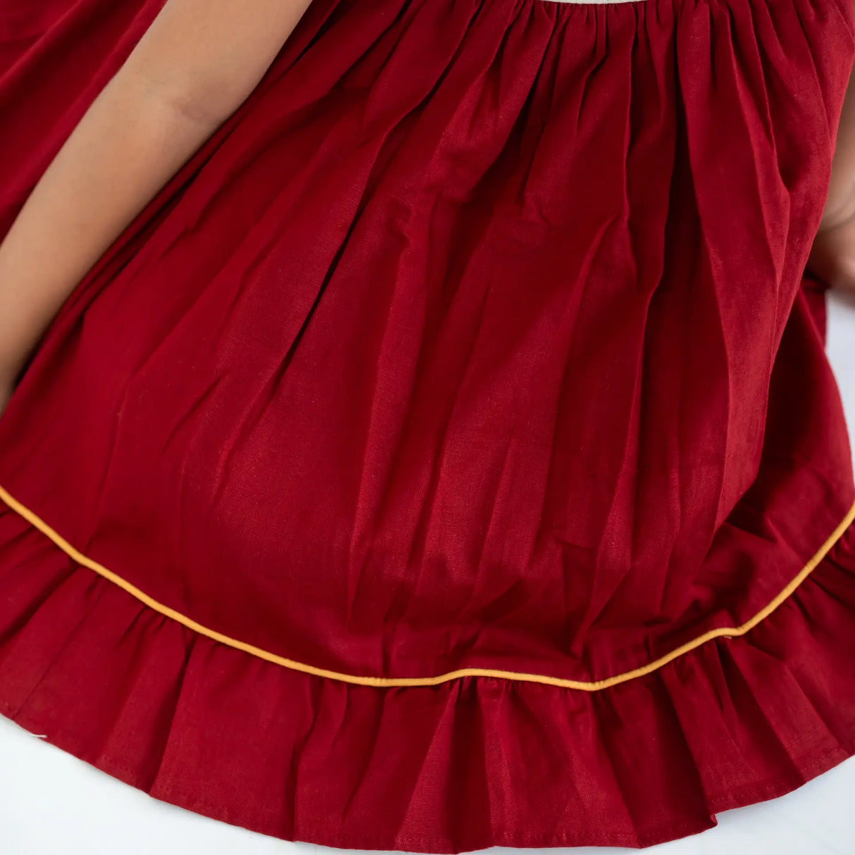 Close-up of the cord piping details on a red hand embroidered sleeveless cotton dress.