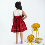 Back view of a girl wearing a red sleeveless cotton dress with hand embroidery.