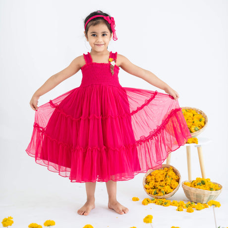 Girl posing in a pink hand-embroidered crochet nylon tulle sleeveless dress, playfully stretching the skirt.