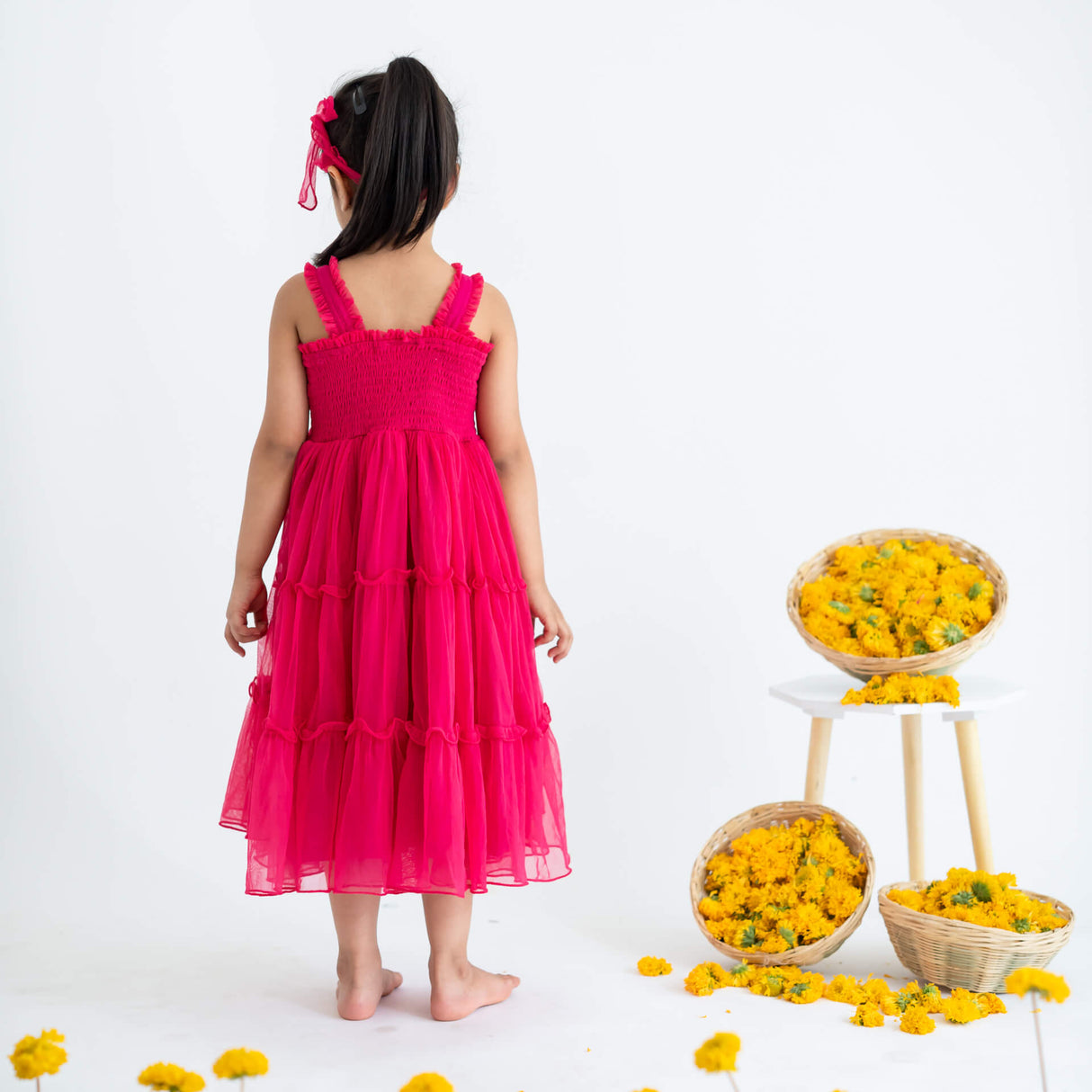 Girl seen from behind, wearing a pink hand-embroidered crochet nylon tulle sleeveless dress.