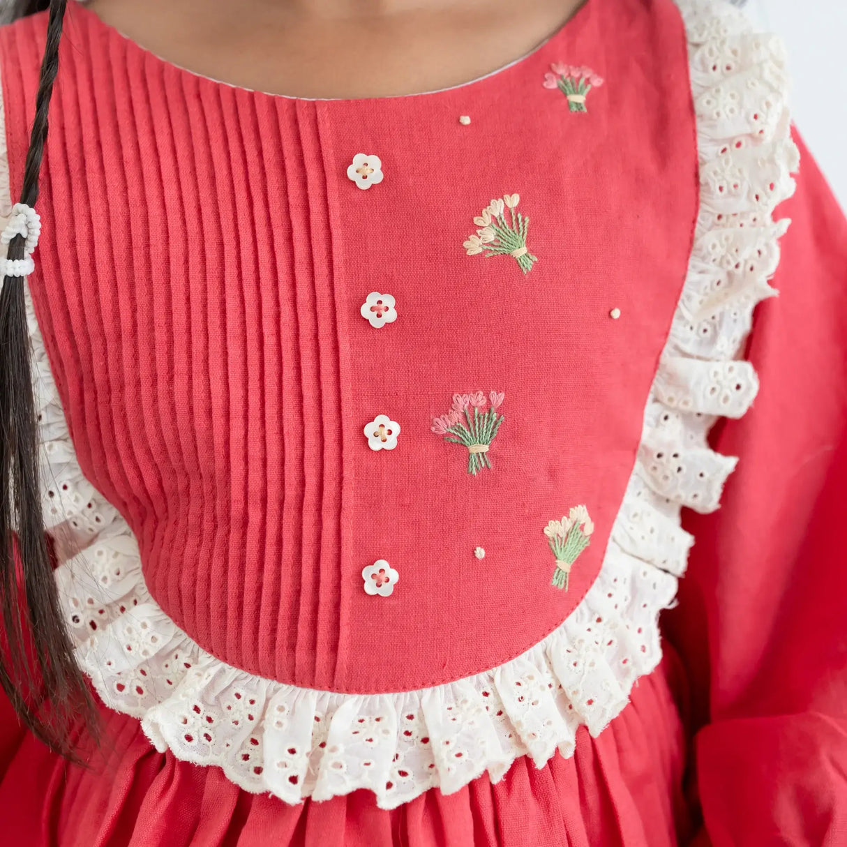 "Close-up of the pleated and embroidery details in the coral pleated yoke embroidered cotton long sleeves dress."