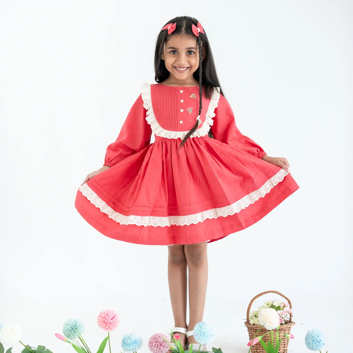 "A little girl dressed in a coral pleated yoke embroidered cotton long sleeves dress."