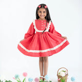 "A little girl dressed in a coral pleated yoke embroidered cotton long sleeves dress."