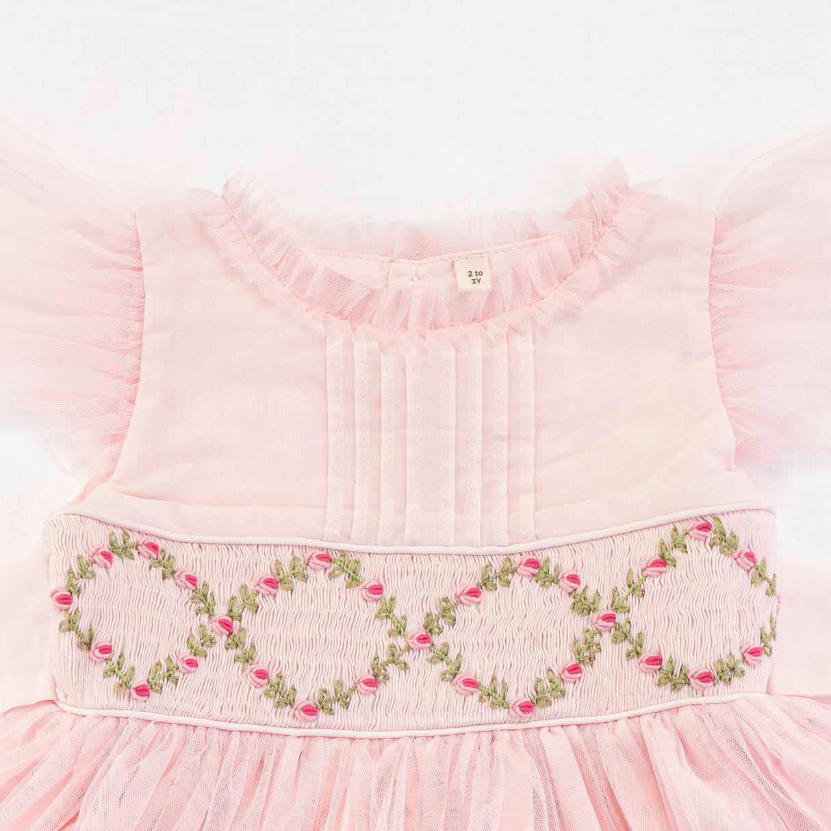 Close-up of the smocking and embroidery details of the pink smocked girls dress