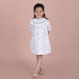 girl wearing an ivory print hand-smocked bishop dress