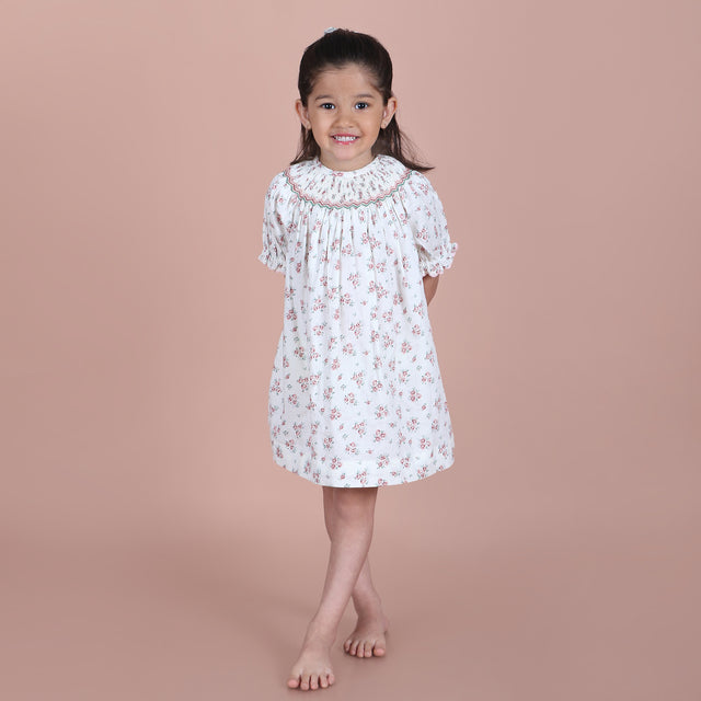 girl wearing an ivory print hand-smocked bishop dress