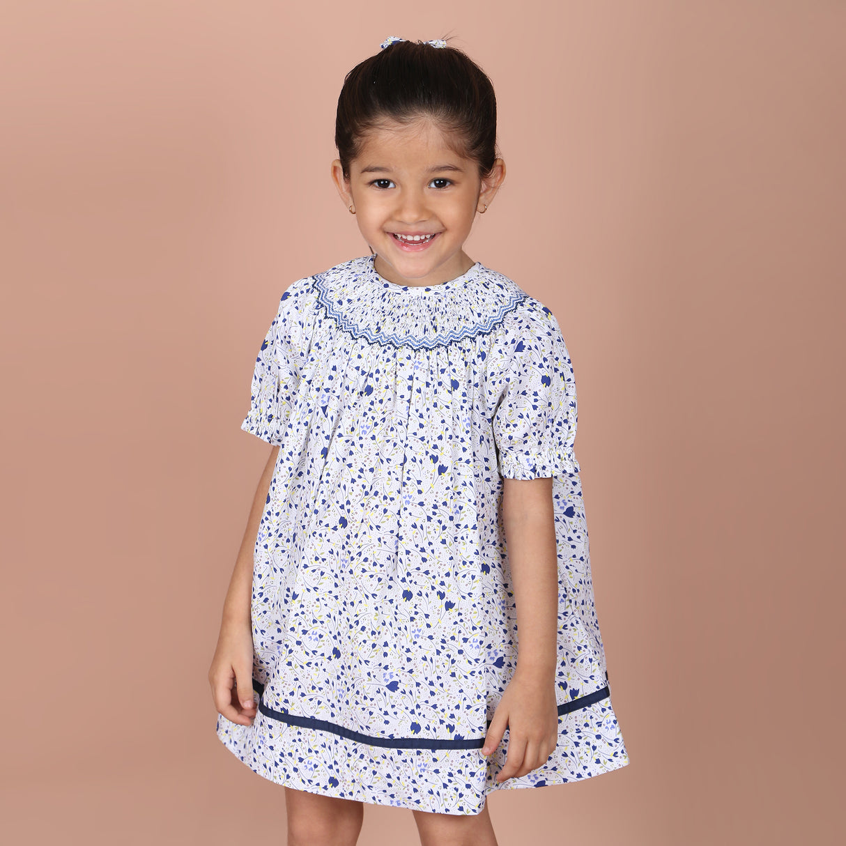 girl wearing a white and navy print hand-smocked bishop dress