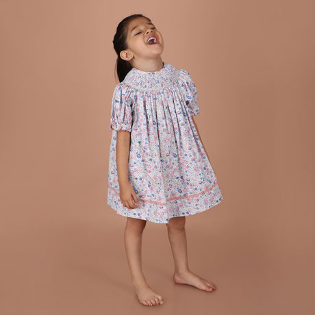 girl wearing a pastel floral hand-smocked bishop dress