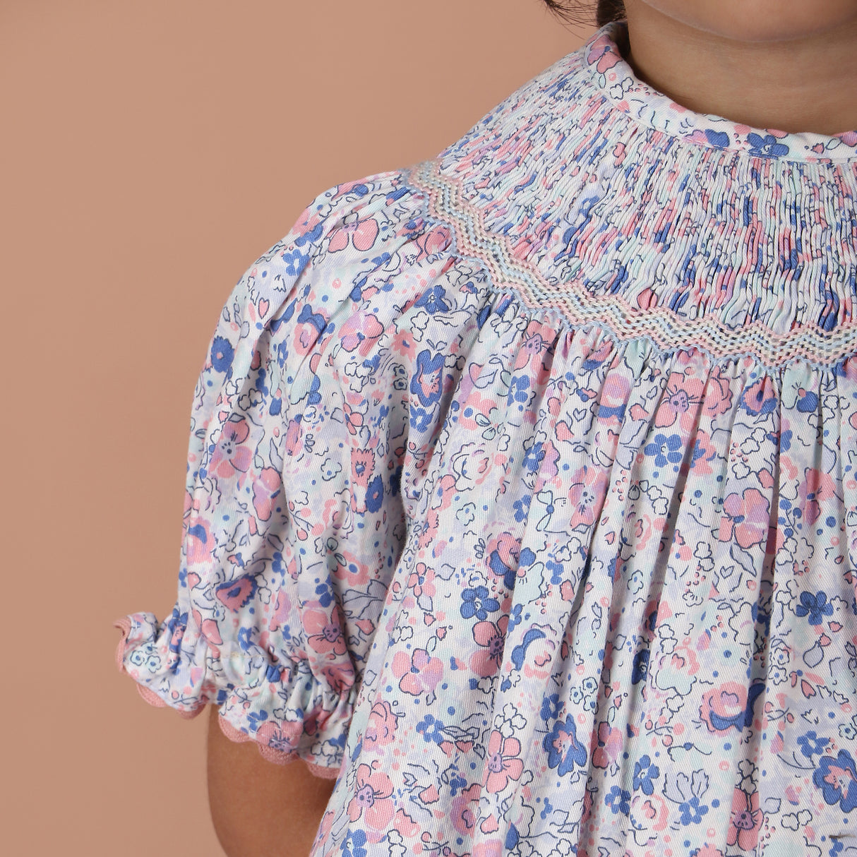 close-up of hand-smocked embroidery on the neckline with ric rac trim on the sleeves