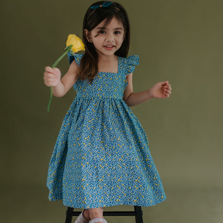 a little girl dressed in blue citrus print dress
