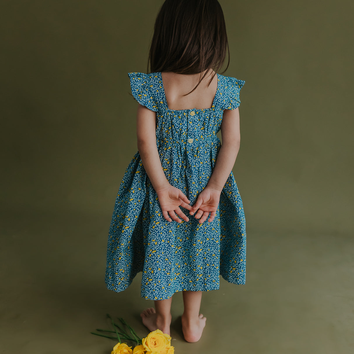 back view of a little girl dressed in blue citrus print dress
