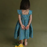 back view of a little girl dressed in blue citrus print dress
