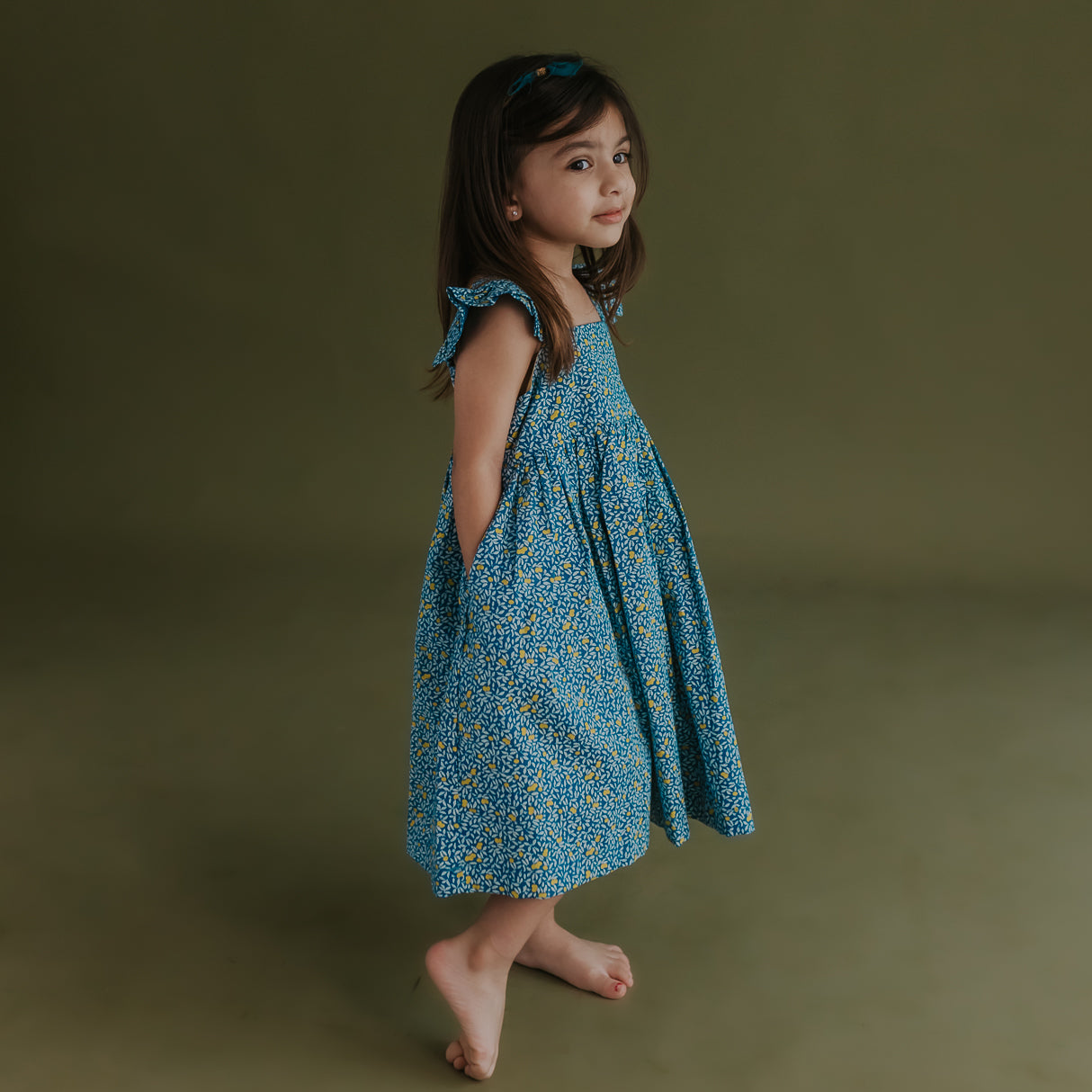 side view of little girl dressed in blue citrus print dress