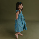 side view of little girl dressed in blue citrus print dress