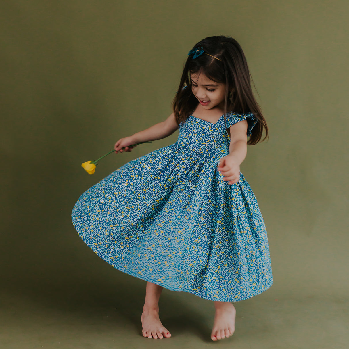 a little girl twirling in the blue citrus print dress