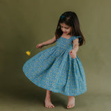 a little girl twirling in the blue citrus print dress