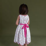 backview pf the little girl dressed in hakoba pink scallop hem dress and closeup of the back bow tied