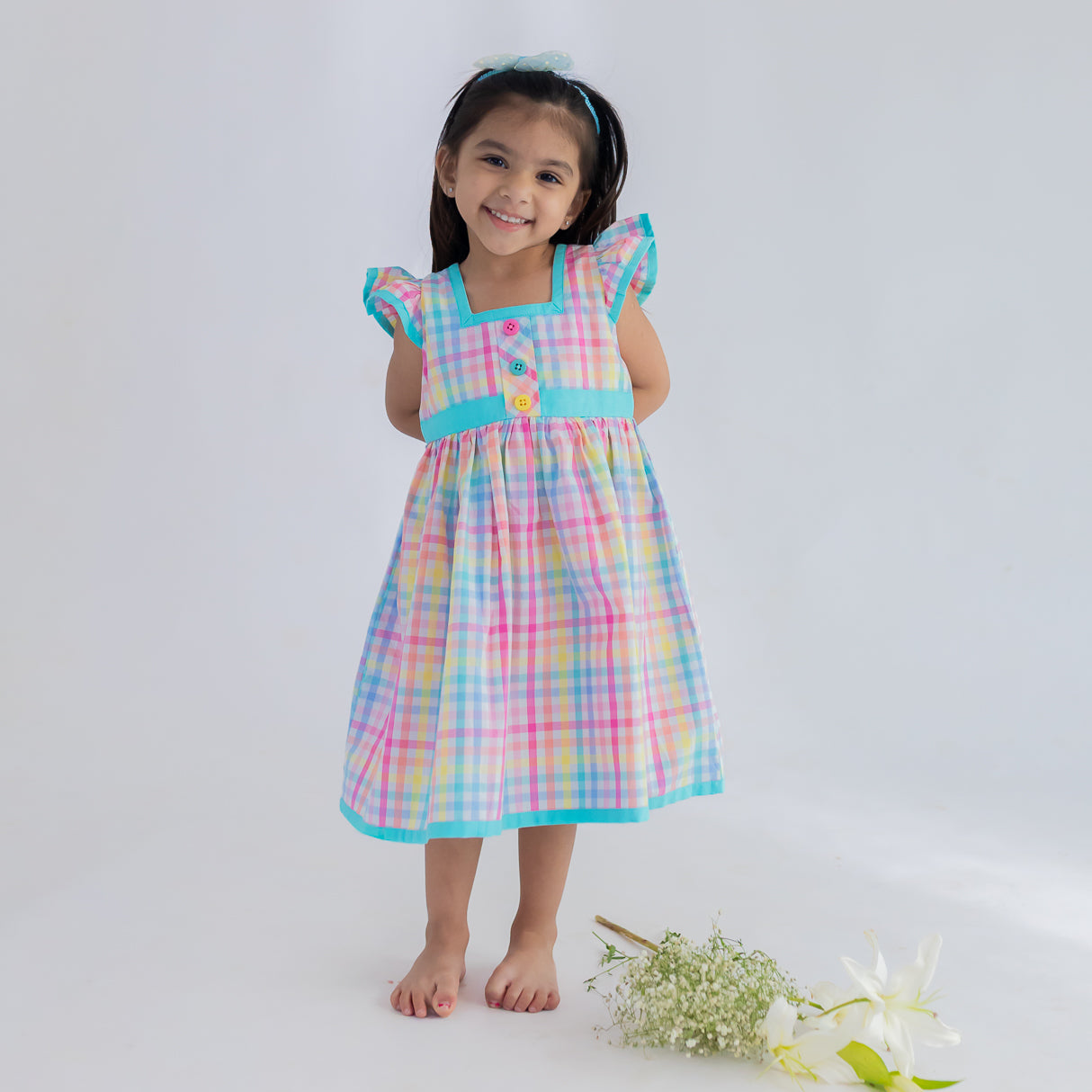 a little girl dressed in multicolour plaid ruffle sleeve dress