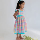 side view of a little girl dressed in multicolour plaid dress