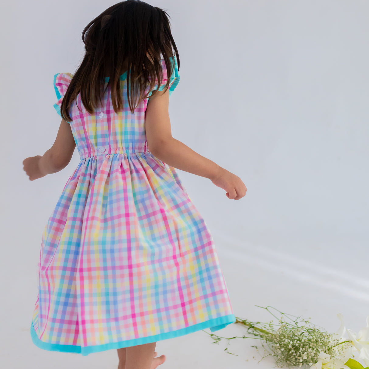back view of girl dressed in multicolour plaid dress
